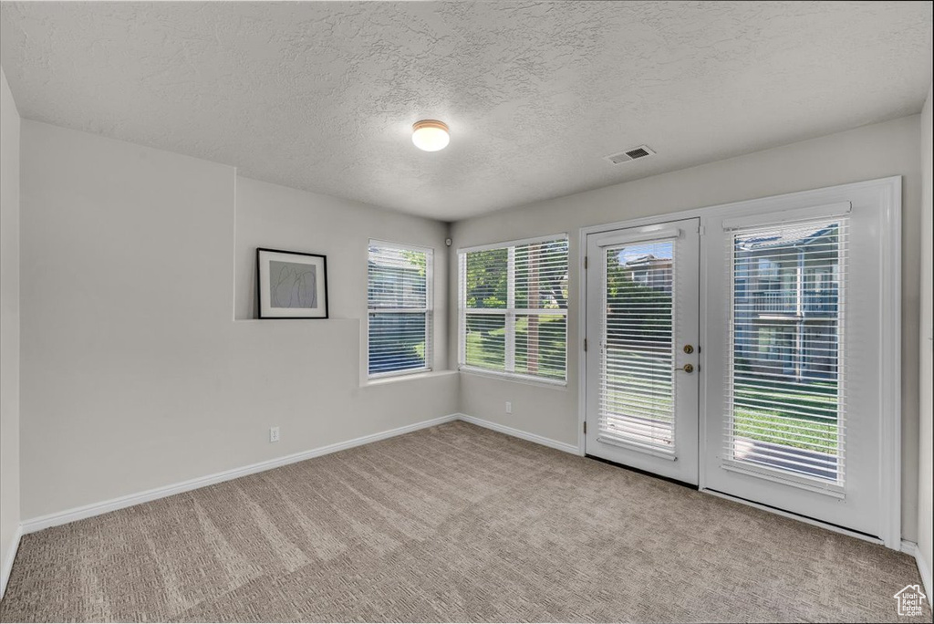 Carpeted spare room with french doors and a textured ceiling