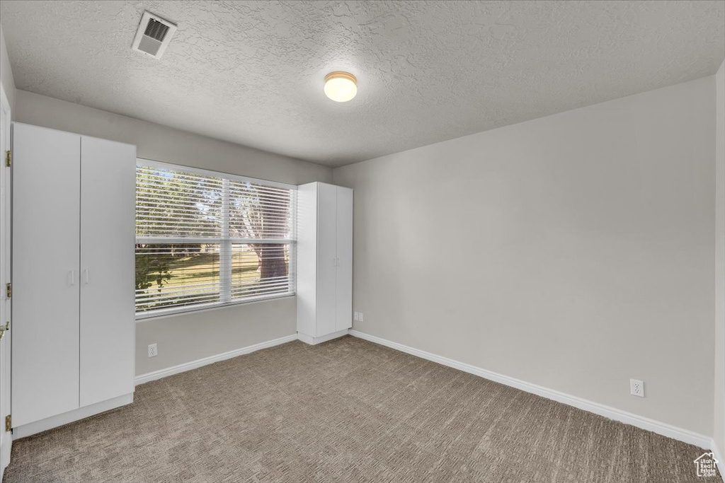 Carpeted empty room with baseboards and a textured ceiling