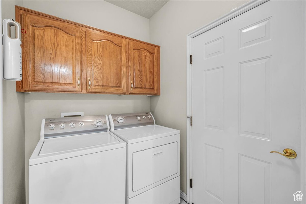 Washroom with washer and clothes dryer and cabinet space