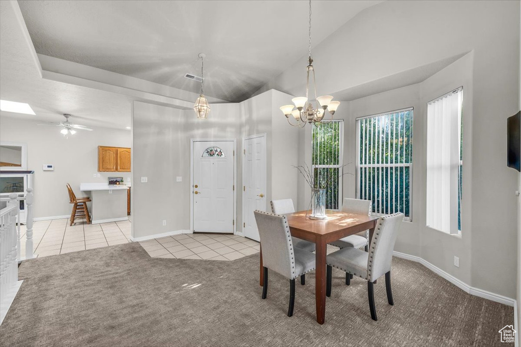 Dining room with light tile patterned floors, a chandelier, light carpet, and lofted ceiling