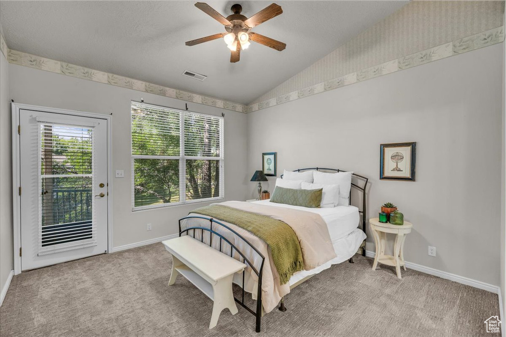Carpeted bedroom with access to outside, vaulted ceiling, wallpapered walls, and ceiling fan