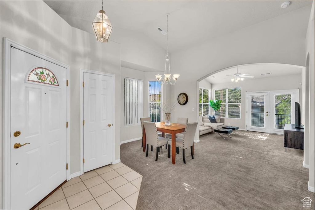 Dining space with arched walkways, light carpet, healthy amount of natural light, a chandelier, and high vaulted ceiling