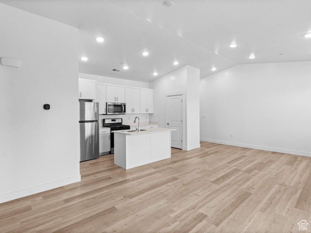 Kitchen featuring appliances with stainless steel finishes, a kitchen island with sink, open floor plan, recessed lighting, and white cabinets