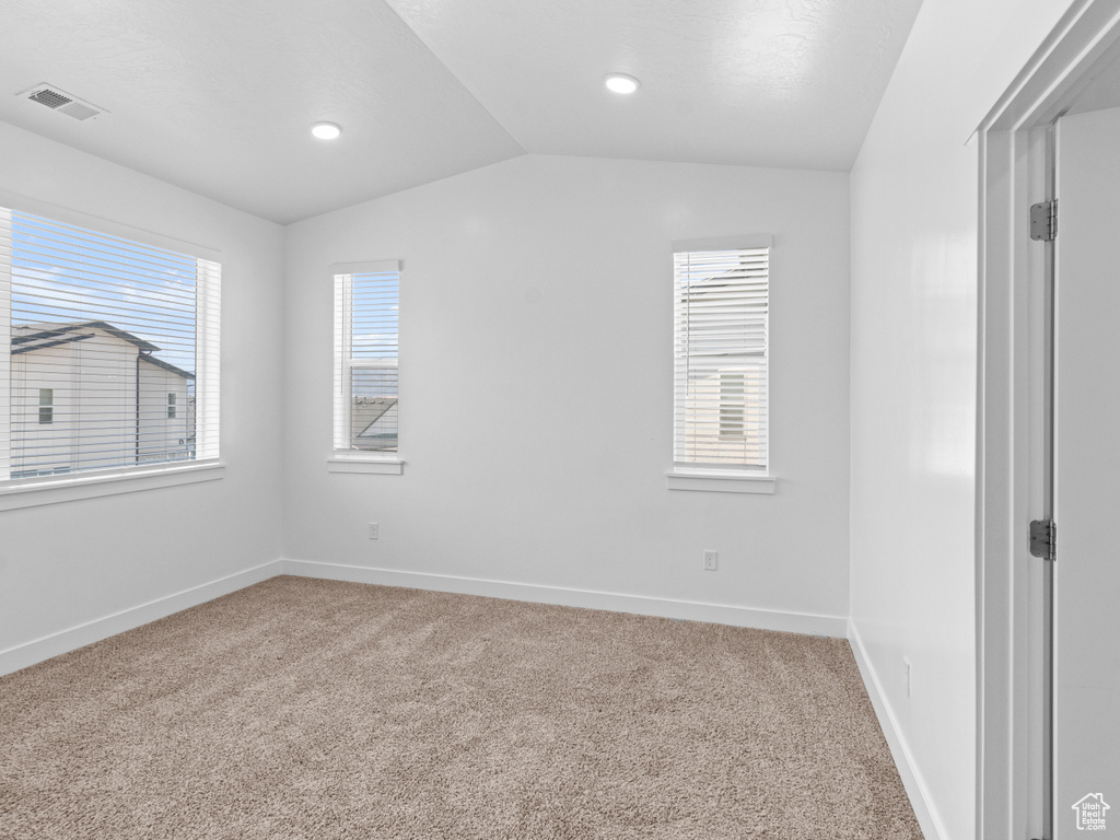 Spare room with vaulted ceiling, light colored carpet, and recessed lighting