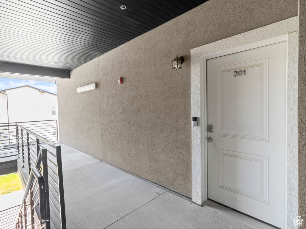 Doorway to property featuring stucco siding and a balcony