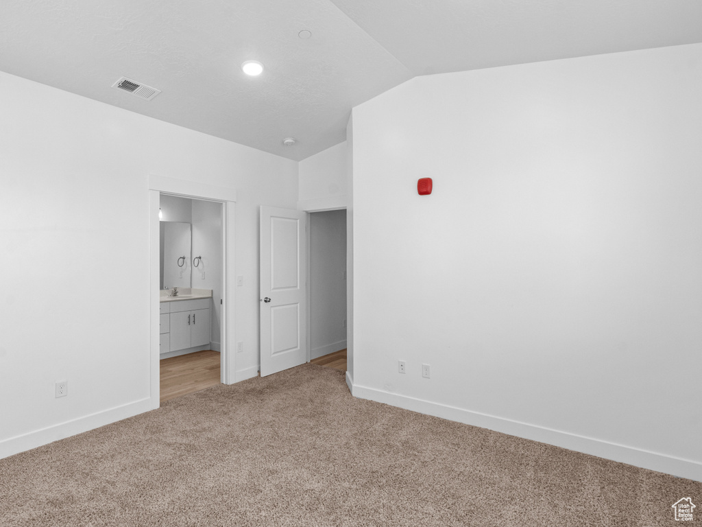 Unfurnished bedroom with carpet, vaulted ceiling, and connected bathroom