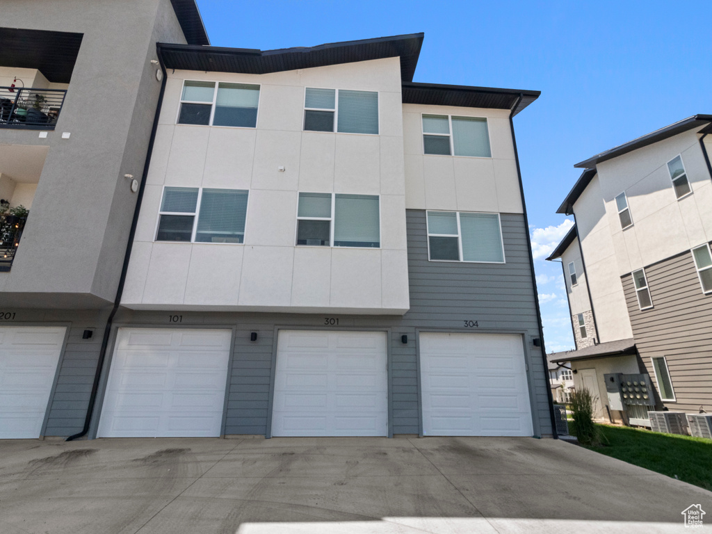 Back of house featuring an attached garage, stucco siding, and driveway