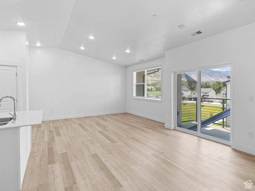 Unfurnished living room with light wood-type flooring, recessed lighting, and vaulted ceiling