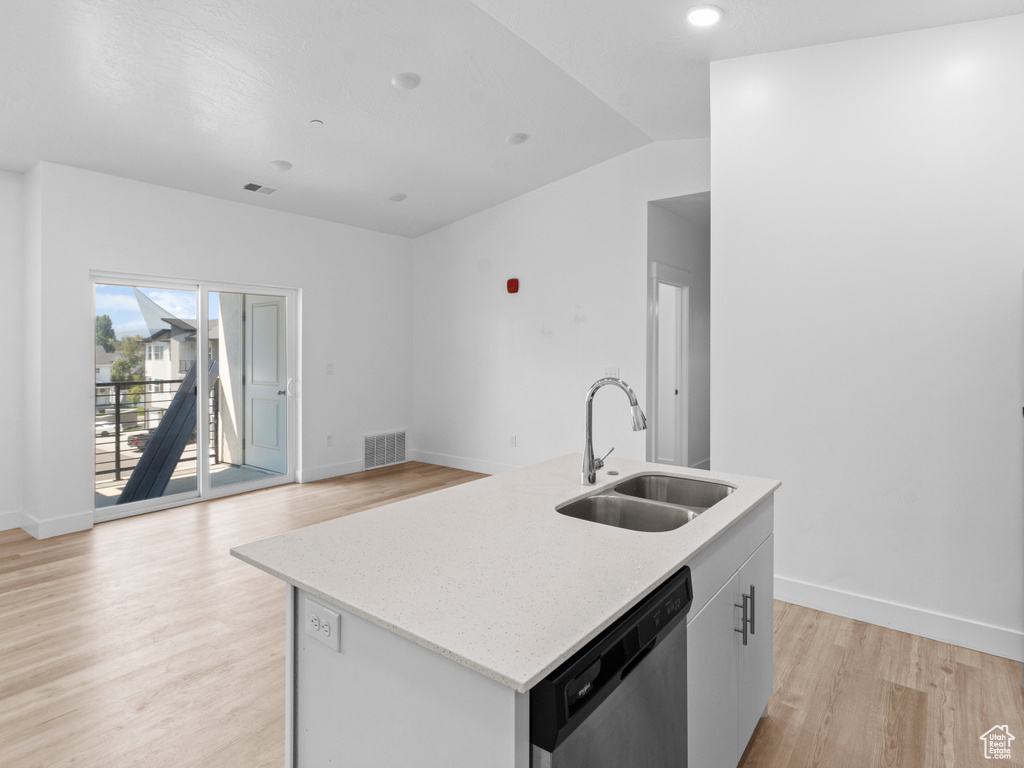 Kitchen featuring dishwasher, light wood-type flooring, an island with sink, light stone countertops, and open floor plan