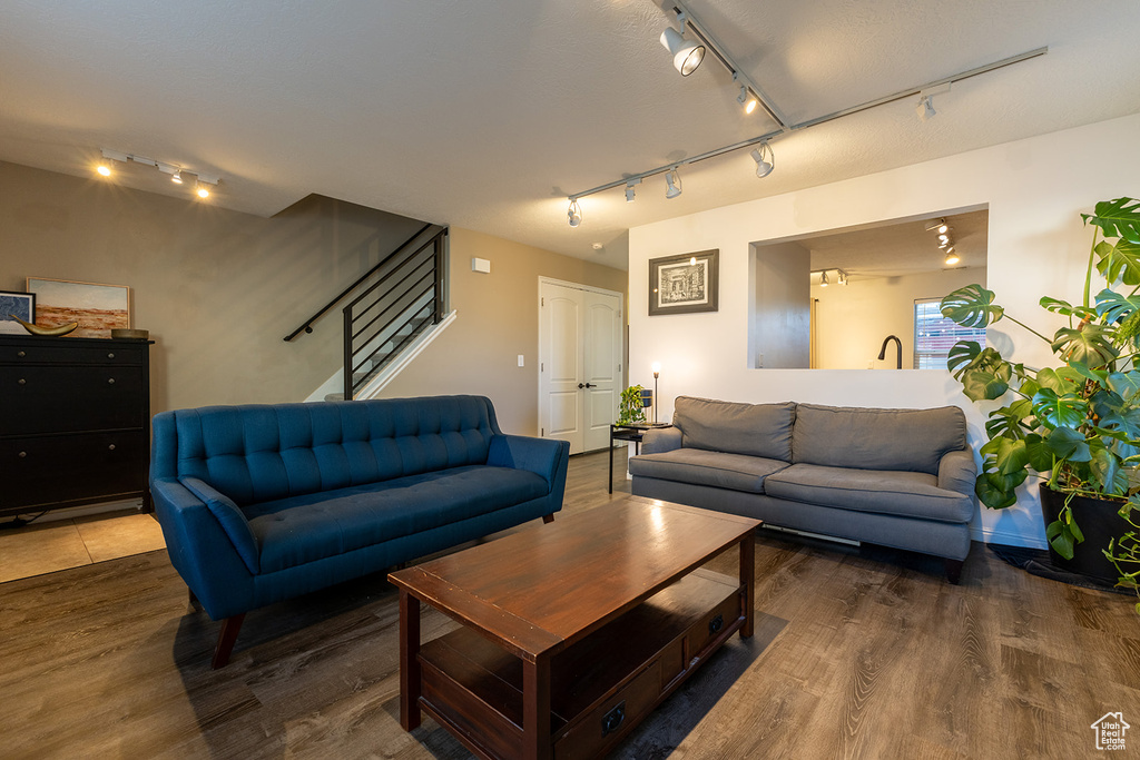 Living area featuring rail lighting, wood finished floors, and stairs