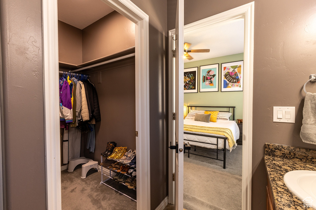 Bathroom with vanity, ceiling fan, and a walk in closet