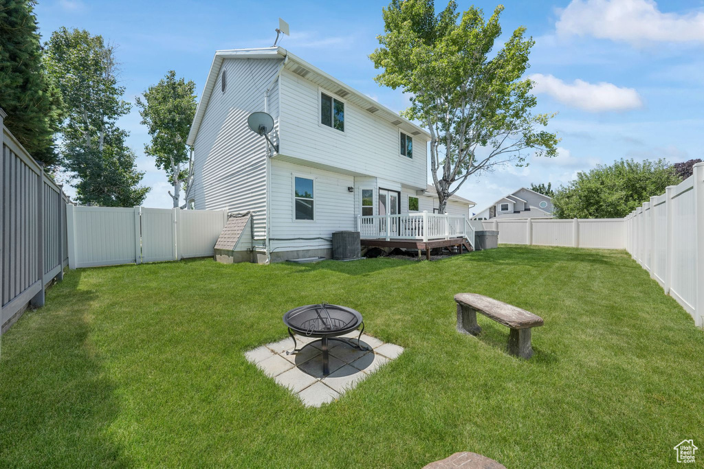 Rear view of property with a fire pit, a fenced backyard, a wooden deck, and a gate