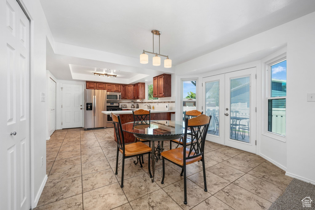 Dining room featuring a tray ceiling, french doors, healthy amount of natural light, and light tile patterned floors