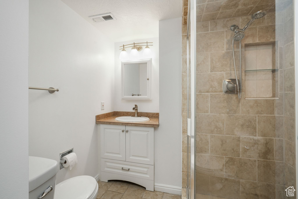 Bathroom featuring tile patterned floors, a tile shower, and vanity