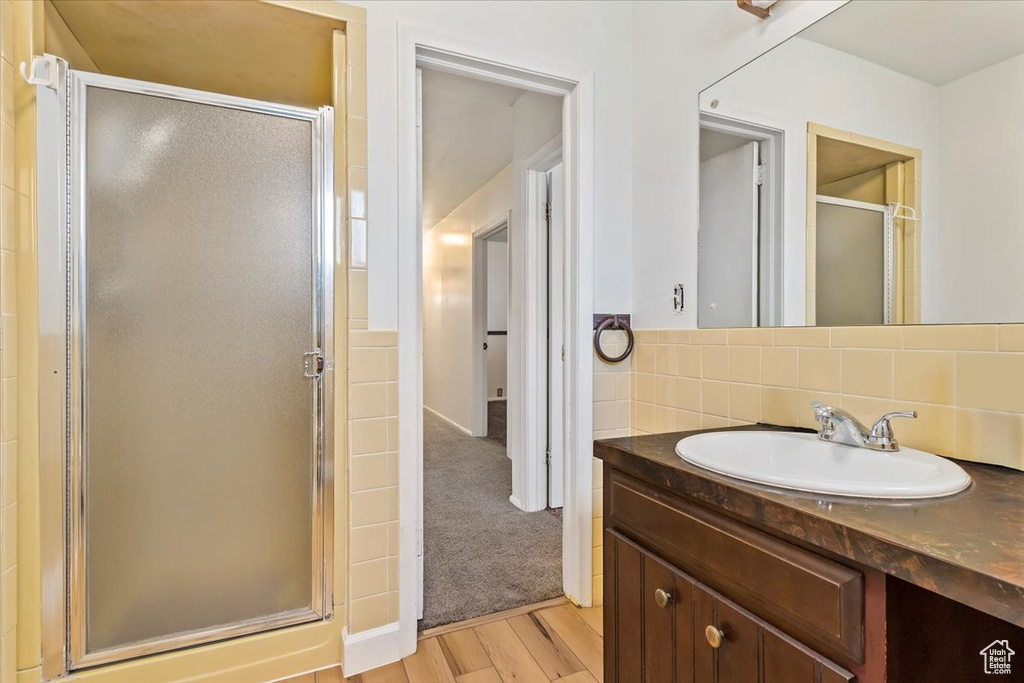 Full bathroom with a shower stall, vanity, wood finished floors, and tasteful backsplash