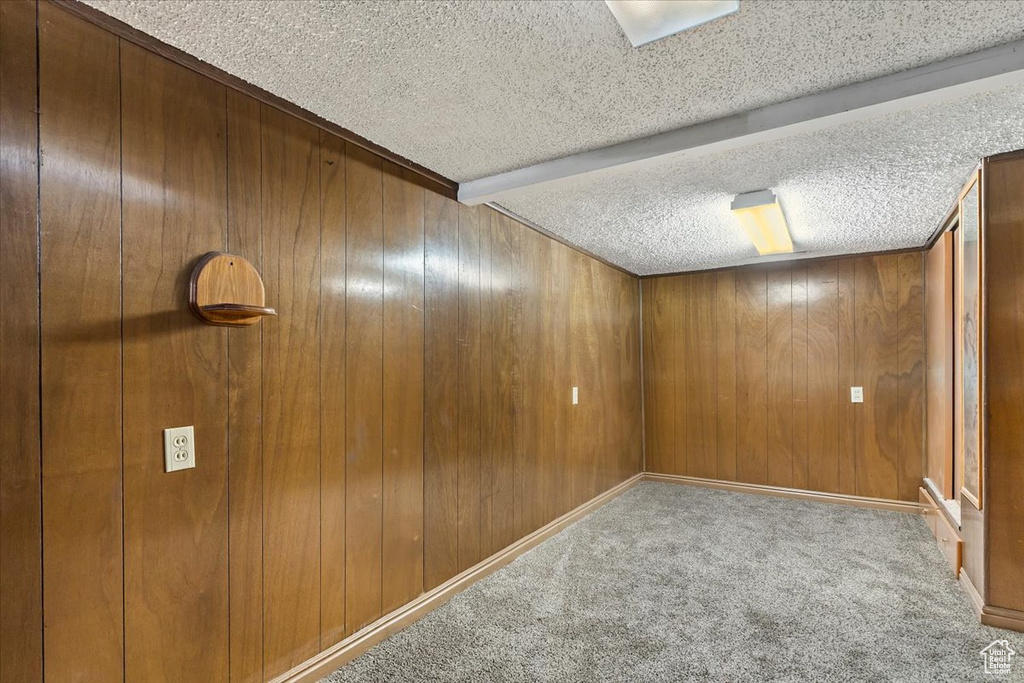Spare room with carpet flooring, a textured ceiling, and wooden walls