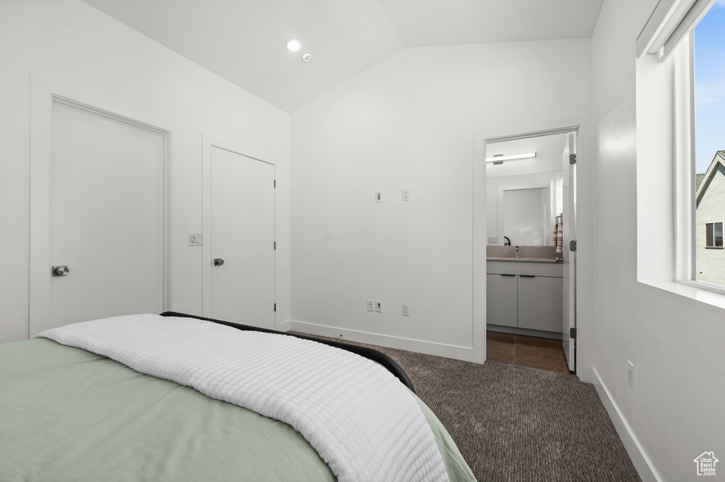 Carpeted bedroom with vaulted ceiling and connected bathroom