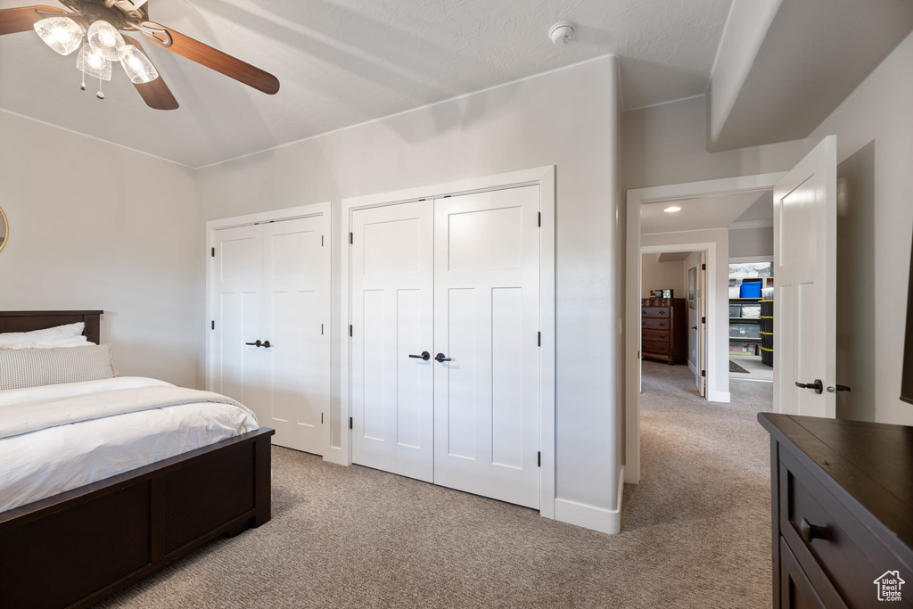 Bedroom featuring light colored carpet, two closets, and a ceiling fan