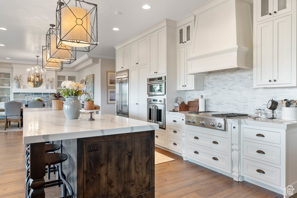 Kitchen featuring appliances with stainless steel finishes, custom exhaust hood, backsplash, white cabinets, and recessed lighting