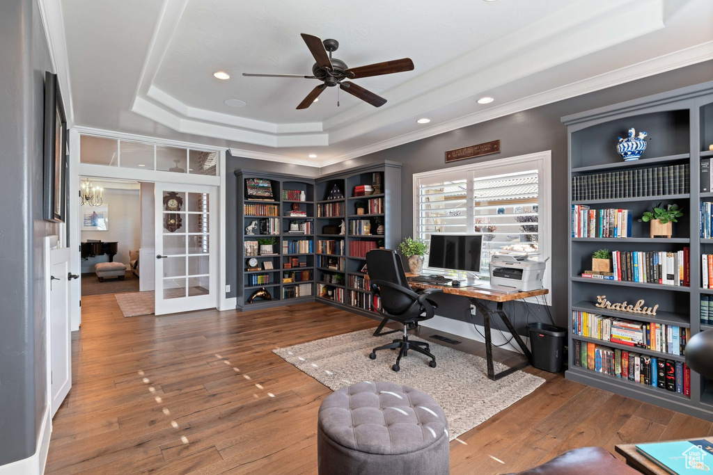 Office with a raised ceiling, a ceiling fan, ornamental molding, wood finished floors, and french doors