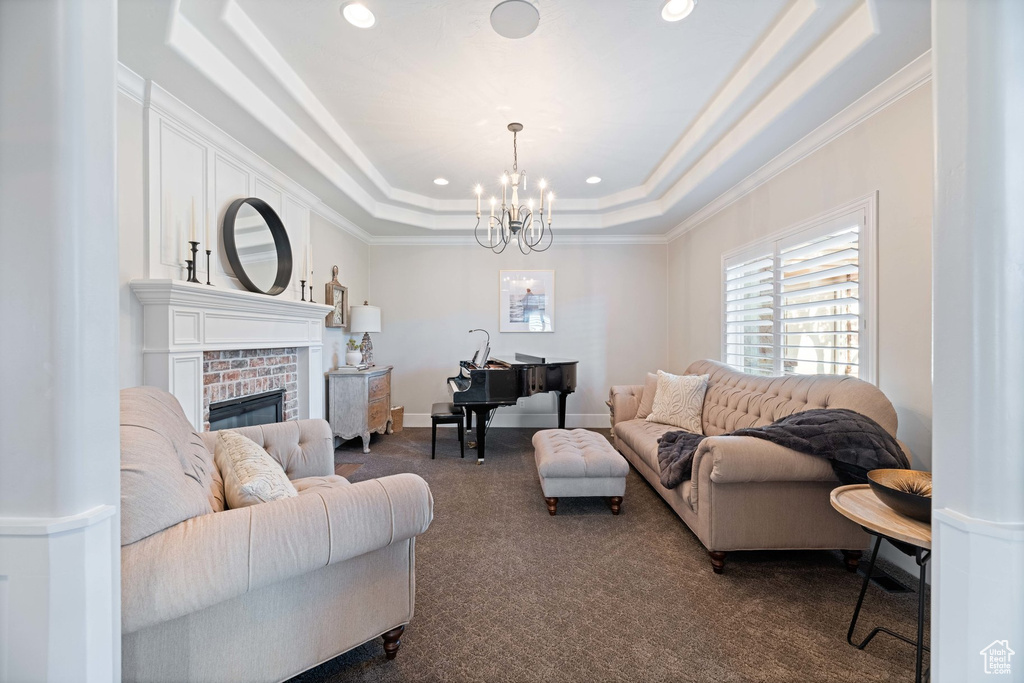 Living area featuring dark carpet, a raised ceiling, crown molding, a chandelier, and recessed lighting