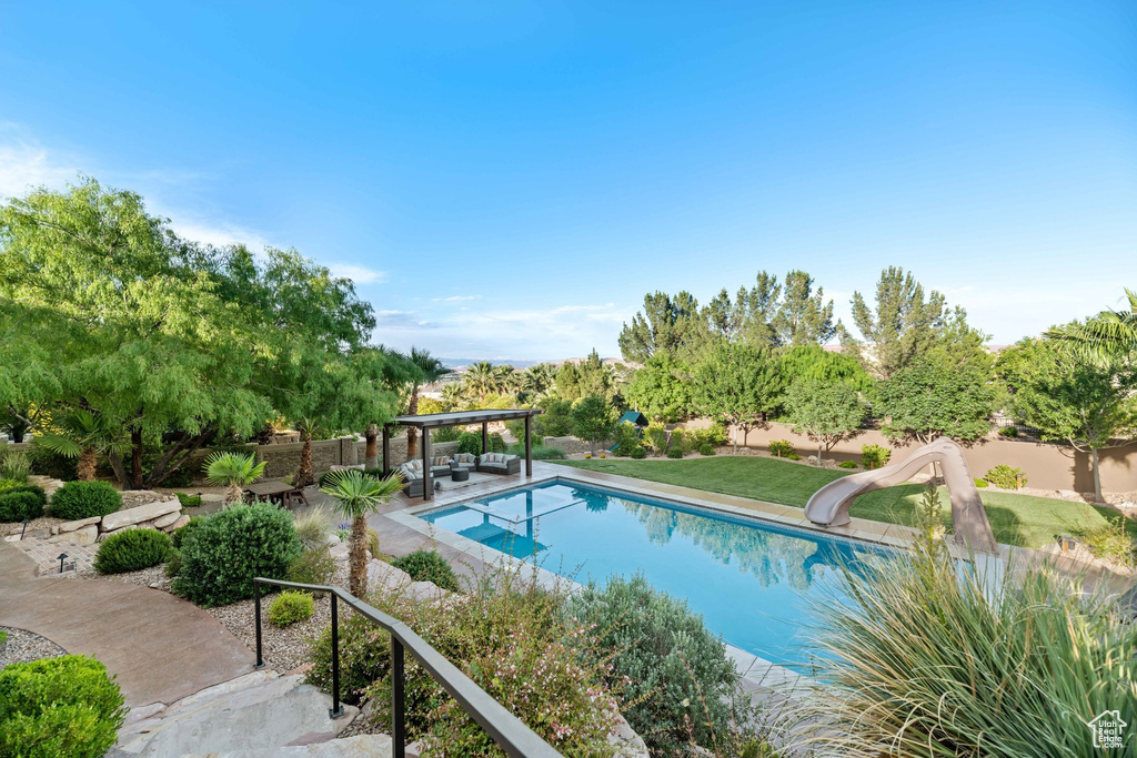 Outdoor pool featuring a water slide, a patio, and a fenced backyard