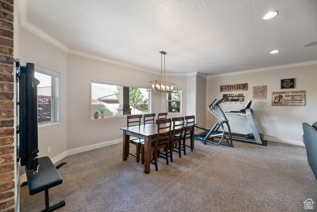Carpeted dining space with healthy amount of natural light, a chandelier, ornamental molding, and recessed lighting