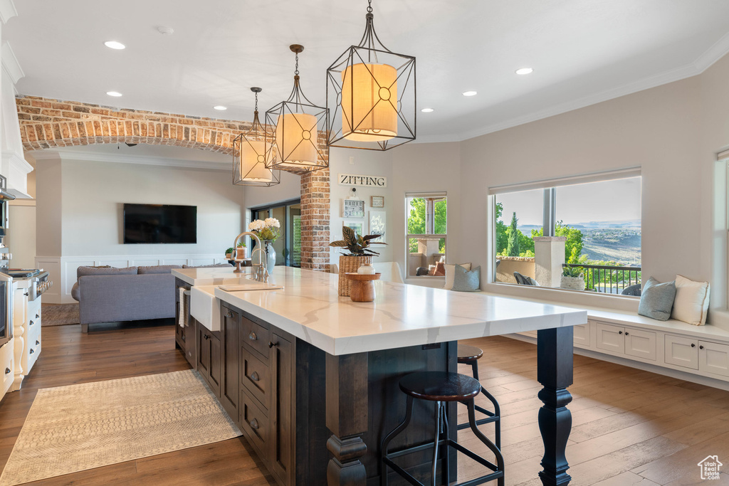 Kitchen with crown molding, open floor plan, recessed lighting, dark wood-type flooring, and light stone countertops
