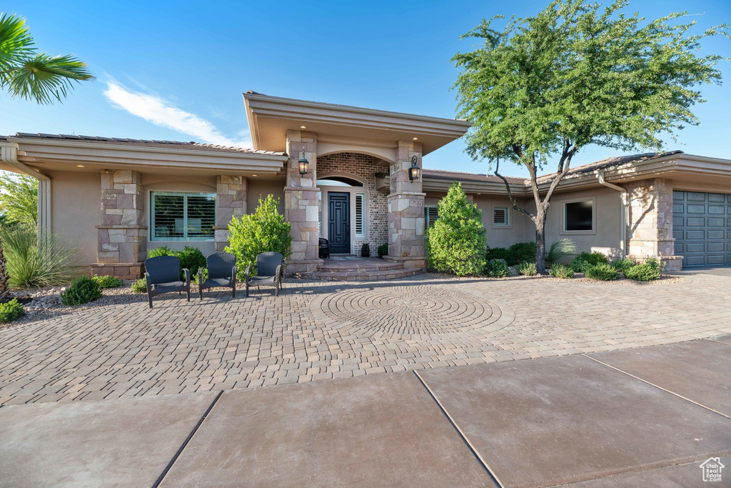 View of front of house with stone siding, stucco siding, driveway, and an attached garage