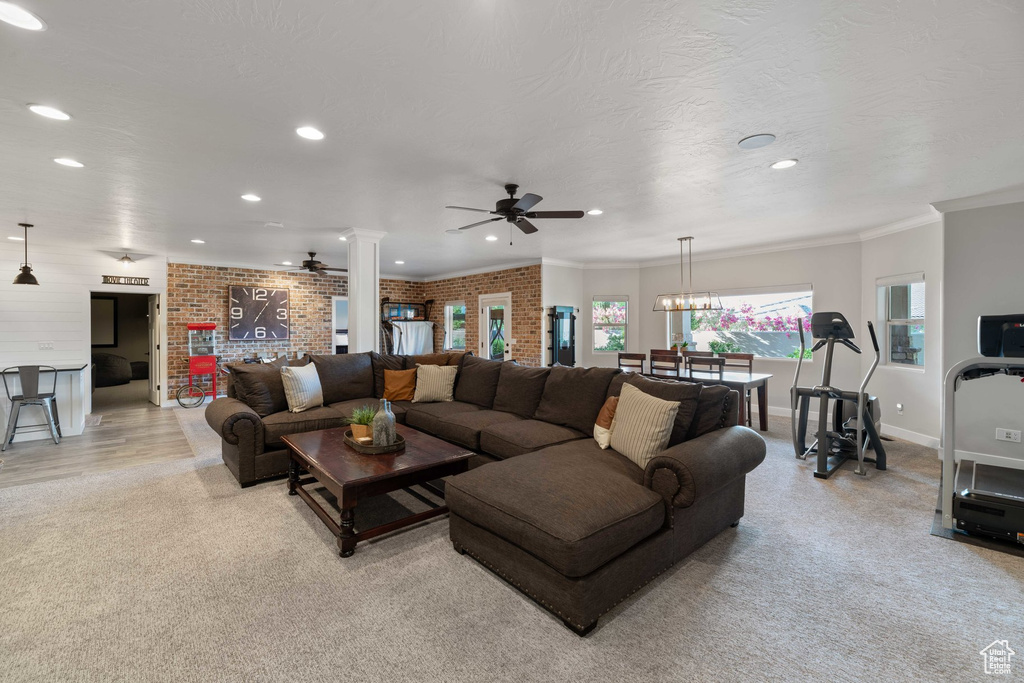 Living area with ceiling fan, decorative columns, recessed lighting, crown molding, and light carpet