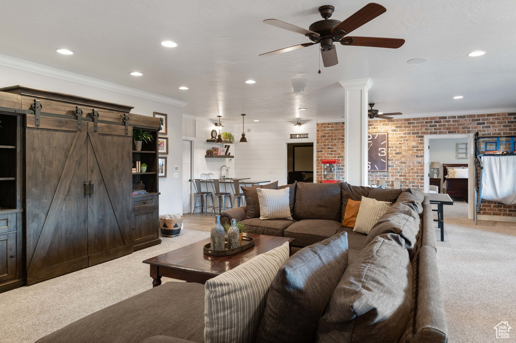 Living room featuring a ceiling fan, light colored carpet, recessed lighting, a barn door, and ornamental molding