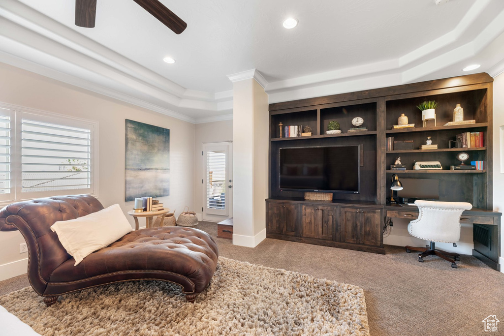 Carpeted living room with ornamental molding, ceiling fan, a tray ceiling, recessed lighting, and built in study area