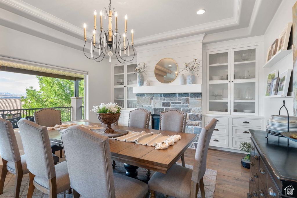 Dining space with a chandelier, dark wood-type flooring, a tray ceiling, recessed lighting, and crown molding