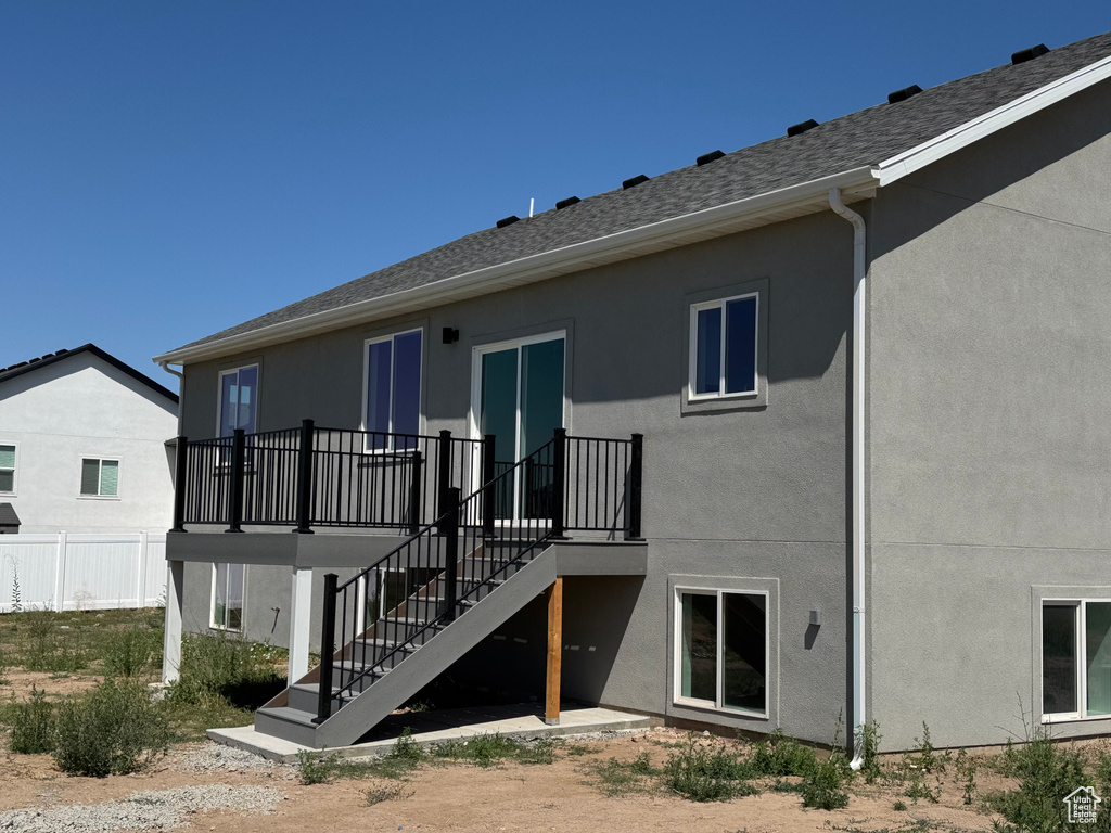 Back of house with stucco siding, stairs, a wooden deck, and a shingled roof