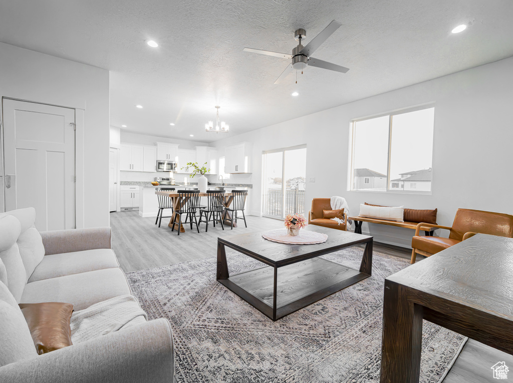 Living area featuring plenty of natural light, recessed lighting, a chandelier, and a ceiling fan