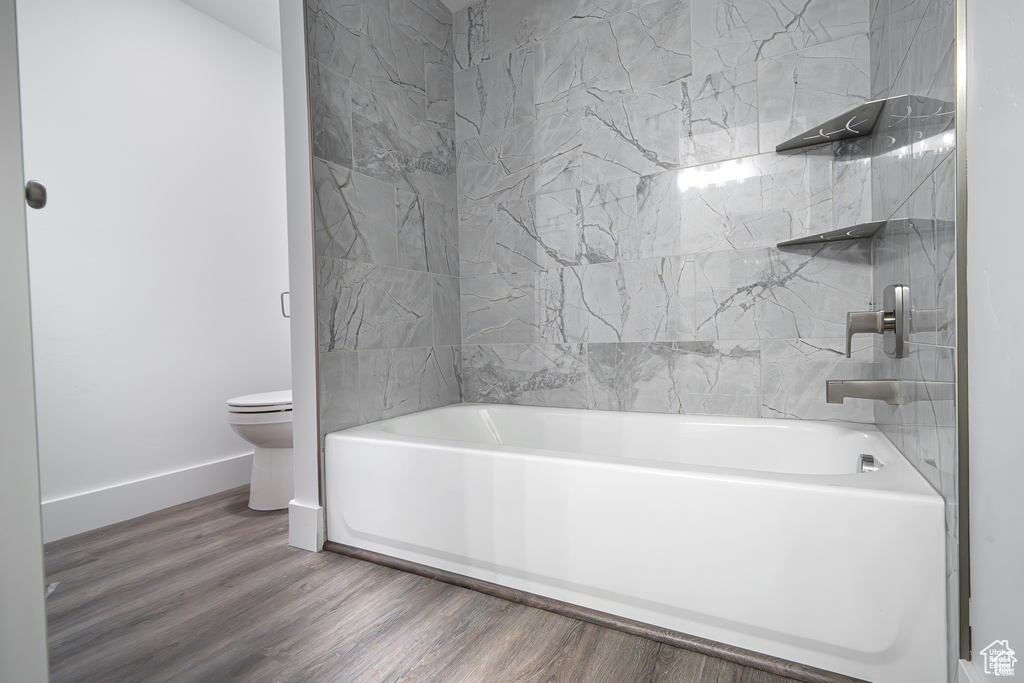Bathroom with wood finished floors and shower / bathtub combination
