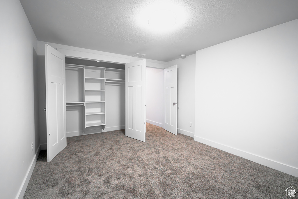 Unfurnished bedroom with a textured ceiling, a closet, and carpet