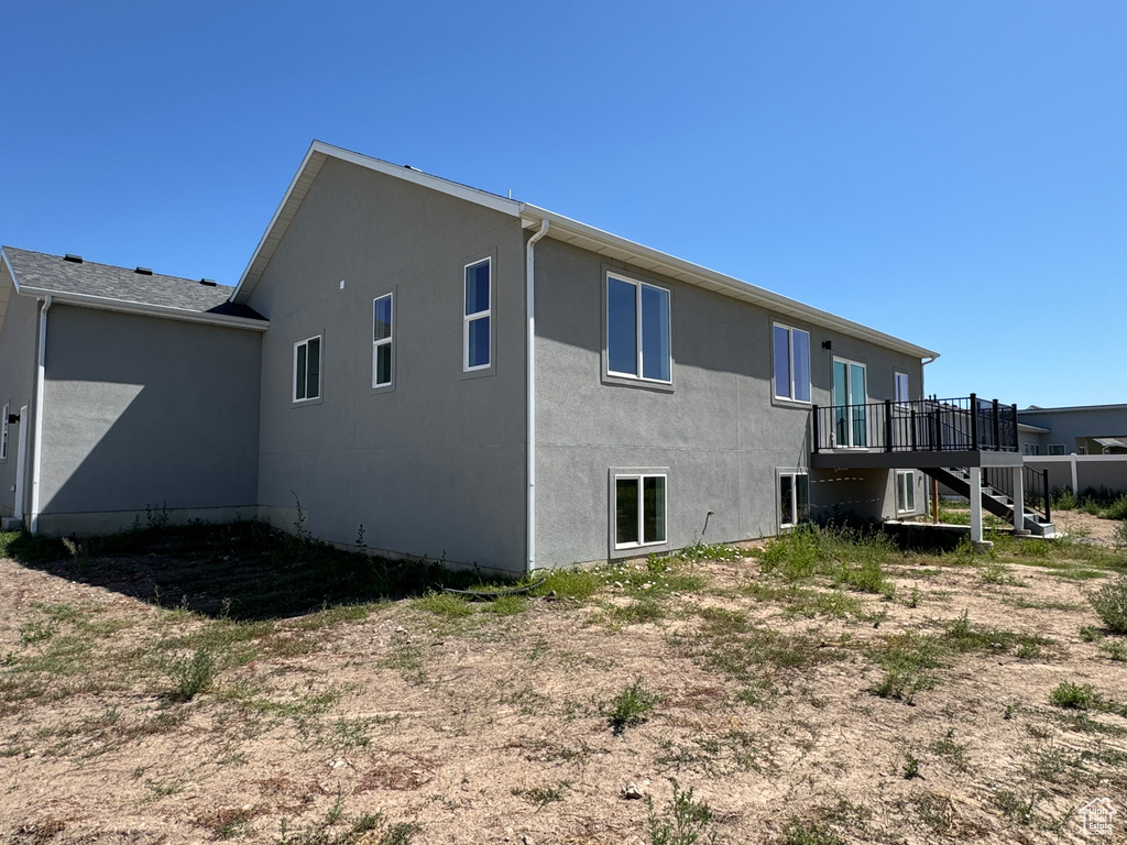 Rear view of property with stairs, stucco siding, and a deck