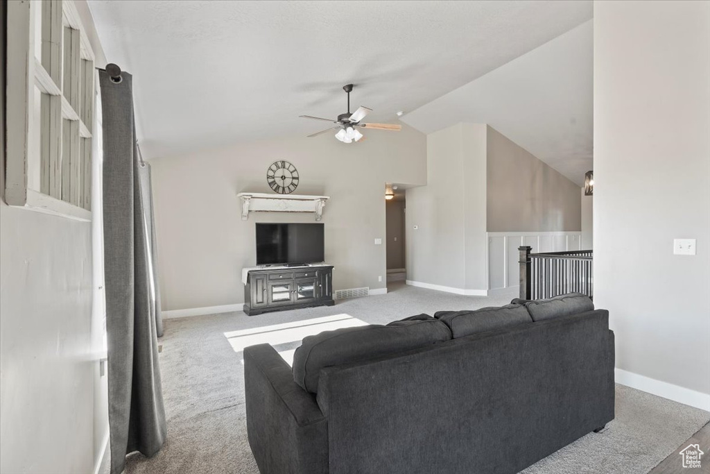 Carpeted living area with a ceiling fan and vaulted ceiling