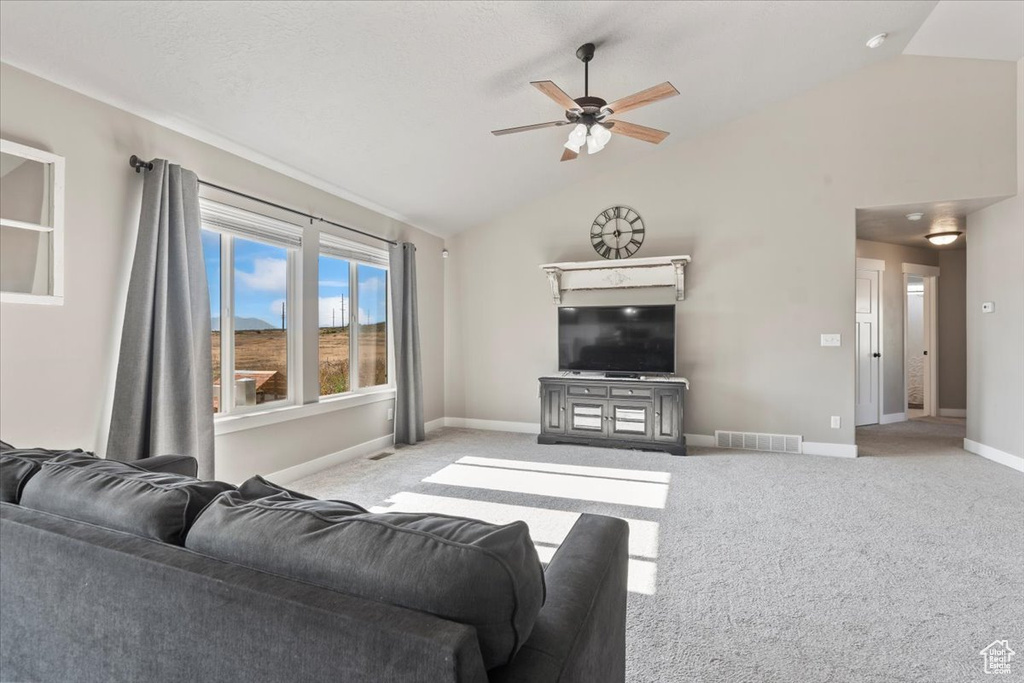 Carpeted living area with ceiling fan and high vaulted ceiling