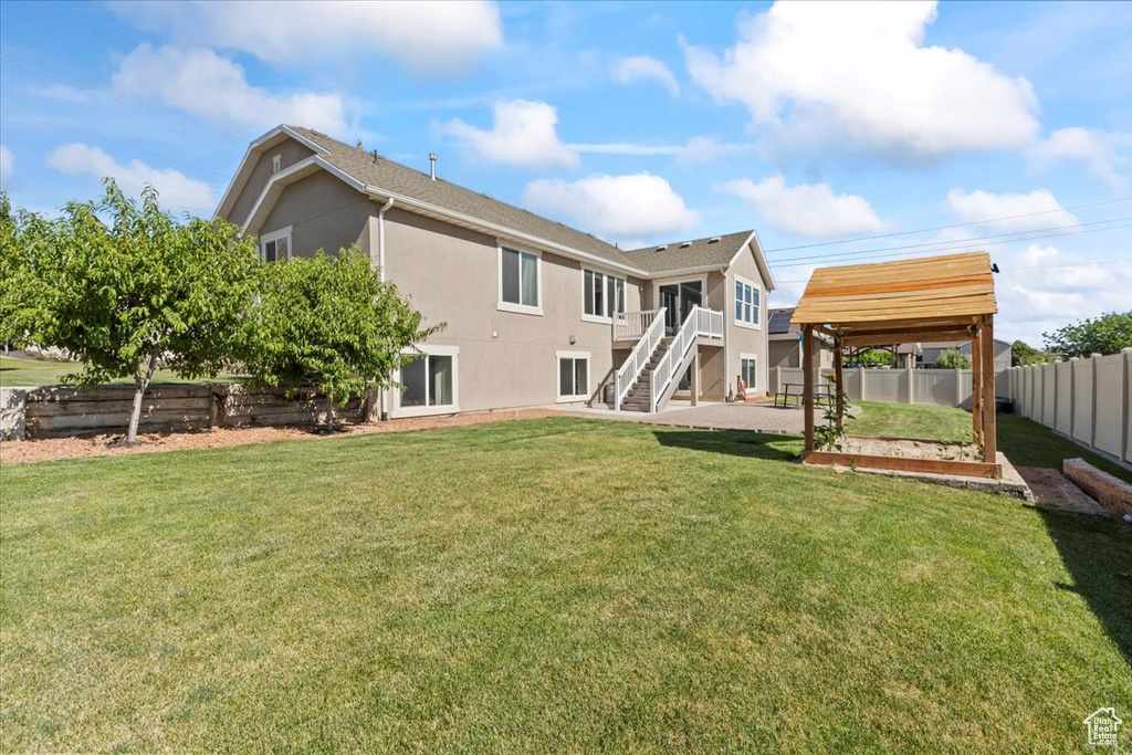 Rear view of property featuring stairway, a vegetable garden, and stucco siding