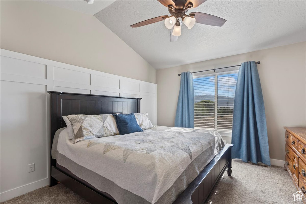 Bedroom with light carpet, lofted ceiling, a textured ceiling, and a ceiling fan