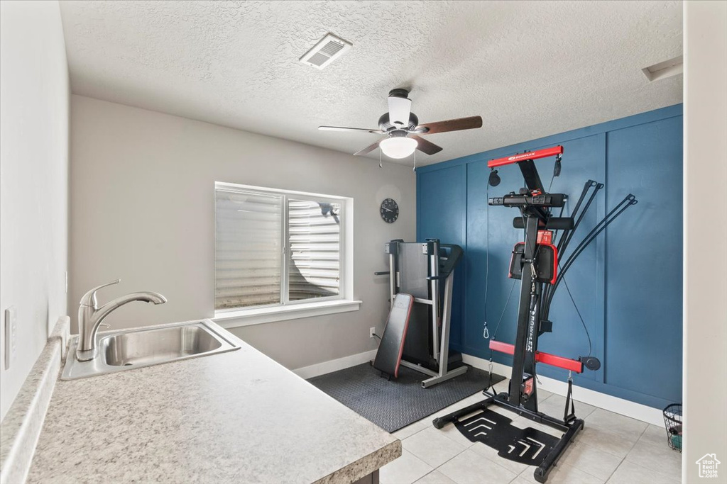 Workout room with ceiling fan and a textured ceiling