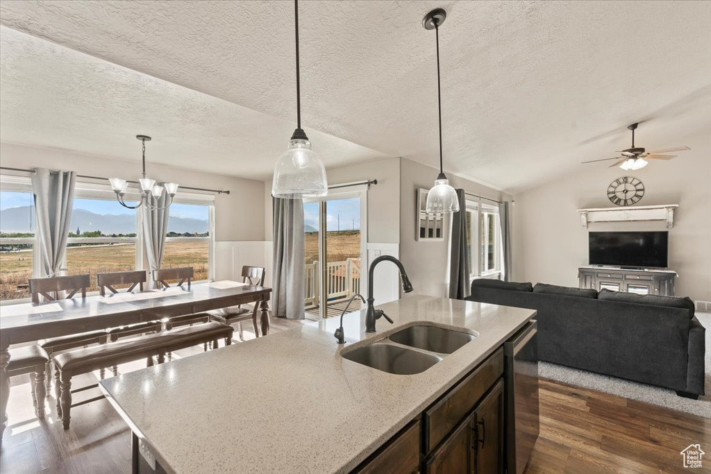 Kitchen featuring dark wood-style flooring, a chandelier, open floor plan, a textured ceiling, and hanging light fixtures