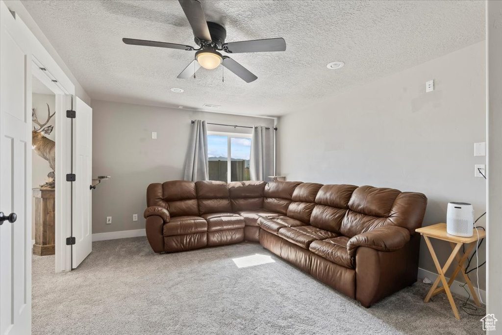 Carpeted living room featuring a textured ceiling and ceiling fan