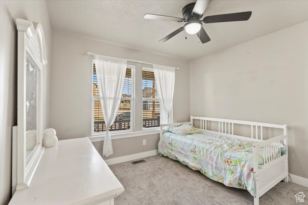 Carpeted bedroom with a ceiling fan and a textured ceiling