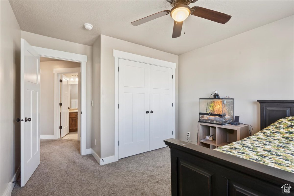 Bedroom with light colored carpet, a closet, and a ceiling fan