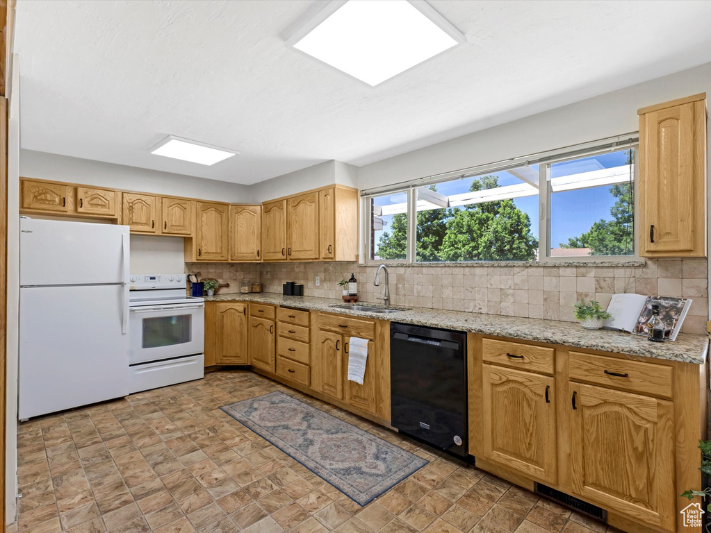 Kitchen with white appliances, tasteful backsplash, light stone counters, and stone finish flooring