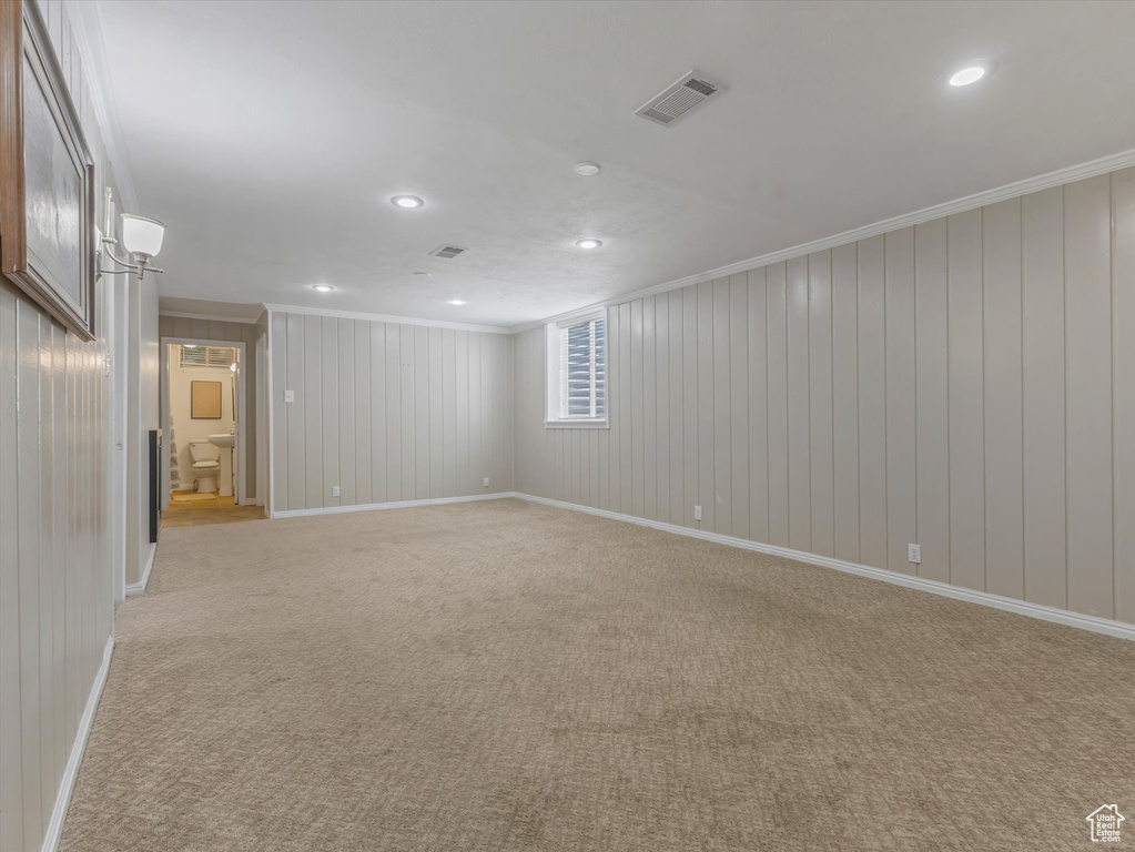Spare room featuring crown molding, light colored carpet, recessed lighting, and wooden walls