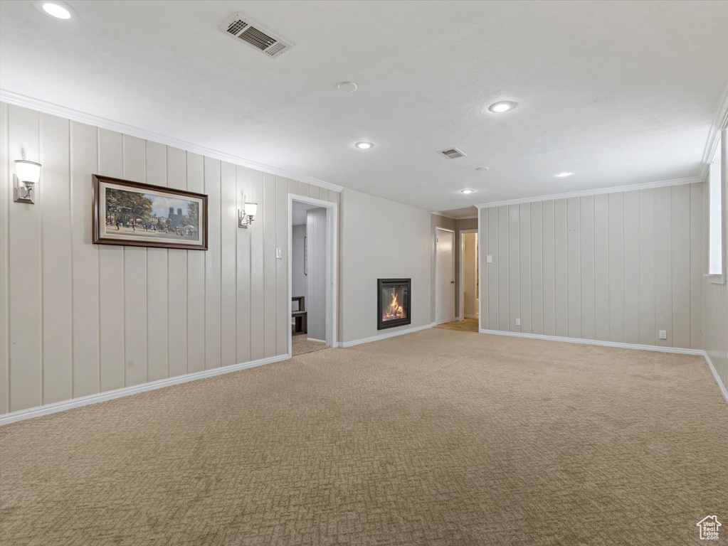 Basement featuring crown molding, recessed lighting, light carpet, and a glass covered fireplace